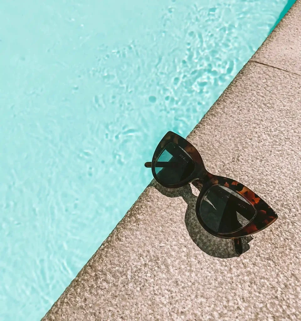 Tortoiseshell cat-eye sunglasses sitting poolside on a sunny day