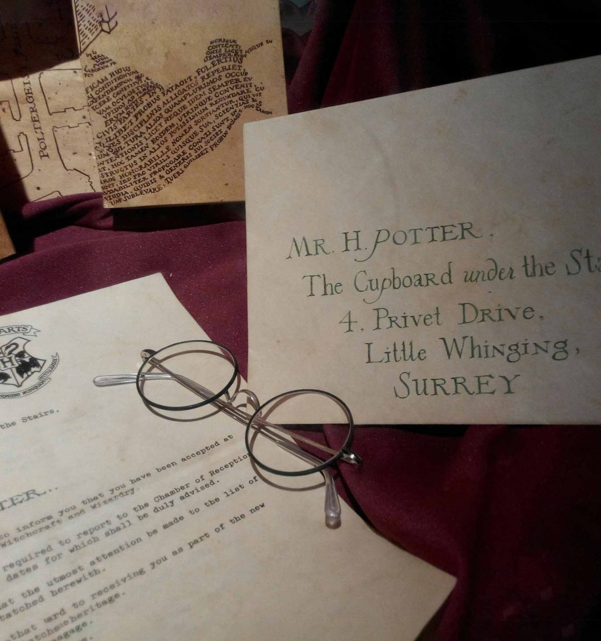 Harry Potter’s iconic round glasses sitting atop a letter from Hogwarts